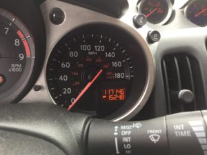 Close-up of a car dashboard showing the speedometer, tachometer, and digital odometer. The speedometer reads 0 MPH, and you can get a Free auto body repair estimate online with your mileage information.